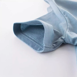 Gros plan sur le bord-côte du T-shirt bleu clair en coton avec coutures surjetées de précision