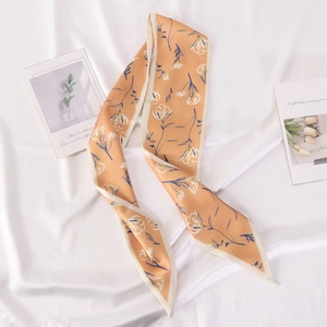 Detailed close-up of orange floral satin scarf with elegant white flower pattern