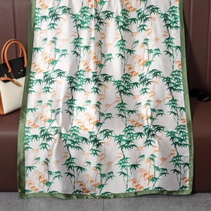 Detailed close-up of glossy satin scarf featuring bamboo leaf patterns and green borders