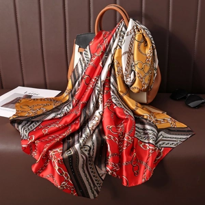 Close-up of vintage printed silk scarf draped over a leather bag with retro chain patterns