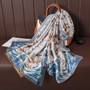 Close-up of elegant floral print silk scarf draped over a leather handbag with sunglasses