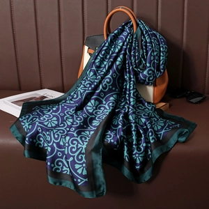 Close-up of silk scarf with vintage floral patterns draped over a stylish handbag