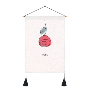 Detail of fabric wall tapestry featuring rose line art with black tassels and wood rod