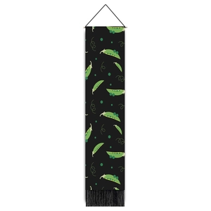 Close-up of green pea pods on a black wall hanging with tassels for kitchen decor