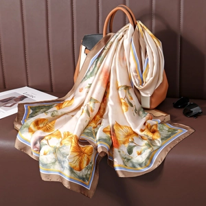 Détail d'un élégant foulard en soie florale drapé sur un sac en cuir à texture satinée