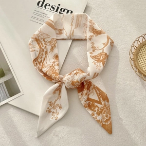 Detail of silk-feel scarf with giraffe and floral print tied in a bow on a magazine