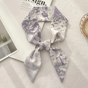Detailed view of a purple French toile pattern silk scarf tied in a bow on a white magazine
