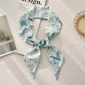 Detail of floral print silk ribbon scarf with blue wave pattern and letter N on fabric