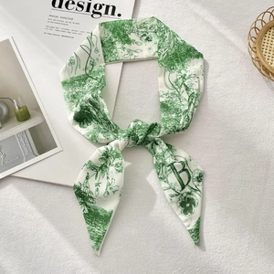 Floral print long silk scarf with green pattern and letter B on a textured white surface