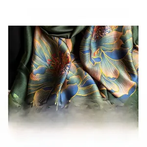 Detail of green silk satin scarf showing intricate lotus print and soft fabric texture