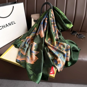 Detail of luxury green faux silk scarf with lotus pattern draped over a gold tray