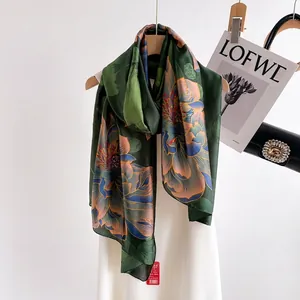 Green silk scarf with floral print hanging on a wooden hanger with luxury accessories