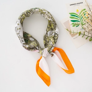 Silk-like floral scarf with green leaf pattern and orange border tied in a bow
