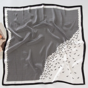 Detailed view of luxury black and white bird print silk scarf with wide black borders