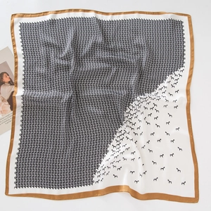 Flat lay of square satin scarf with abstract black pony print and gold border