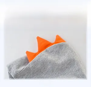 Dettaglio del cappello in maglia grigio per neonati con decorazioni 3D arancioni