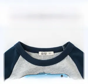 Détail de l'encolure et de l'étiquette de taille 90 sur un t-shirt bleu pour enfant