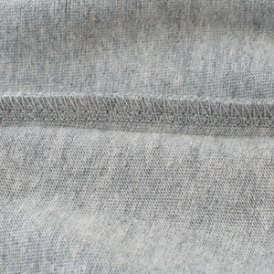 Gros plan sur les coutures plates d'un t-shirt gris à manches longues pour garçon