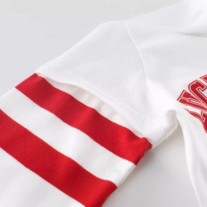 Close-up of white cotton kid shirt sleeve with red sporty stripes and neat stitching