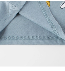 Detail of gray-blue cotton T-shirt hem with precise stitching and shark print for kids