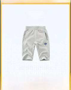 Dettaglio di pantaloncini in cotone grigio chiaro con ricamo a squalo blu sulla gamba