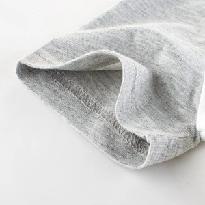 Dettaglio polsino della t-shirt estiva grigia da bambino con doppia cucitura ad ago