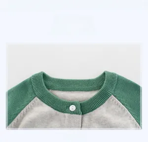 Close-up of contrast crew neck and white button detail on green knit cardigan