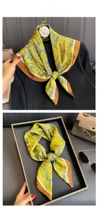 Détail d'un foulard en soie imprimé feuilles vert-jaune avec bordure marron en boîte