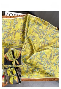 Détail d'un foulard carré jaune satiné avec imprimé de feuilles et texture soyeuse