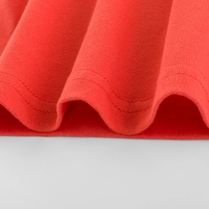 Close-up of red cotton knit fabric detail with neat double-needle stitching on kids' shirt