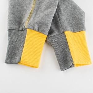Close-up of children's grey sweatpants showing yellow striped ribbed cuffs and stitching