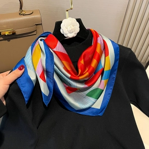 Satin silk square scarf with jumping horse print tied over a black sweater