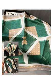 Detail of silk satin scarf featuring teddy bear print and geometric letter M patterns