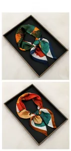 Detail of silk-satin scarf collection showing vibrant ginkgo floral patterns and rolled edges