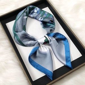 Detailed view of floral silk scarf featuring grey-blue satin texture and green leaf print
