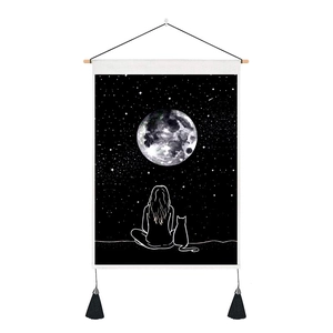 Detail of artistic moon and star tapestry featuring wooden rod and decorative tassels