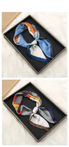Detail of two floral silk scarves tied in bows on a black tray with white faux fur