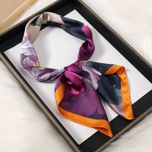 Detail of silk square scarf featuring purple floral patterns and orange stitched edges