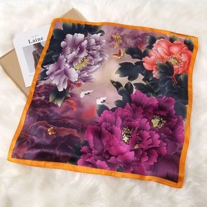 Detail of floral silk scarf featuring peony and crane patterns on white faux fur background