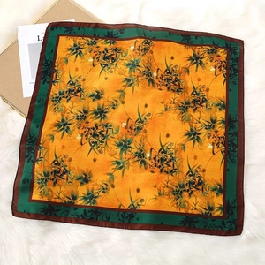 Close-up of floral print satin square scarf on white faux fur background with gift box