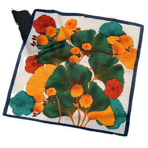 Flat lay of a 70cm silk-like square scarf with ginkgo print and navy blue borders