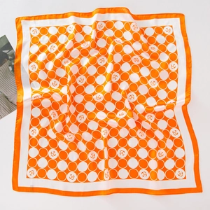 Détail d'un foulard carré soyeux avec des pois orange et des motifs floraux