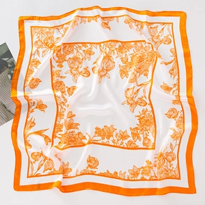 Detailed flat lay of a floral silk scarf with vibrant orange edges on white background
