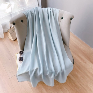 Gros plan d'une écharpe en coton bleu clair drapée sur une chaise sous lumière douce
