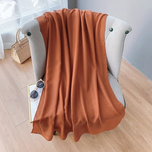 Texture détaillée d'un châle en coton et lin rouge rouille drapé sur une chaise