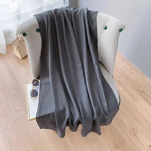 Gros plan d'une écharpe en lin et coton gris foncé avec texture fine et coutures de qualité