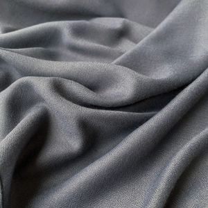 Gros plan sur l'écharpe en lin gris foncé montrant le tissage sergé et la texture mate