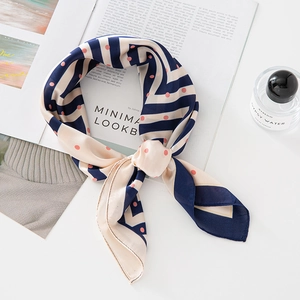 Foulard en soie élégant avec rayures marine et pois roses sur un bureau blanc
