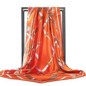 Vue détaillée d'un foulard en soie orange avec motifs de chaînes dorées et finition satinée