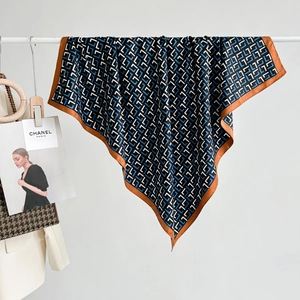 Navy blue and orange geometric silk scarf displayed with stylish fashion magazines